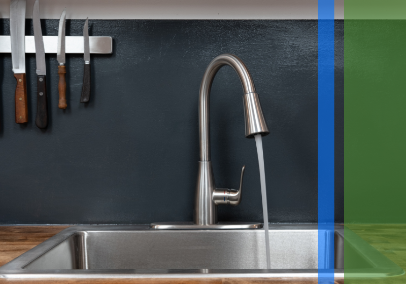 A stainless steel sink with the tap turned on and water flowing.