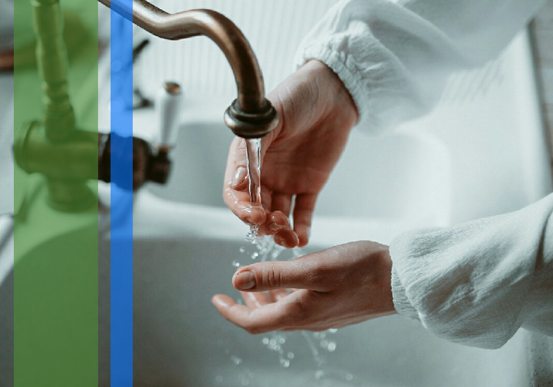 Water flowing out of a sink over a woman's hands.