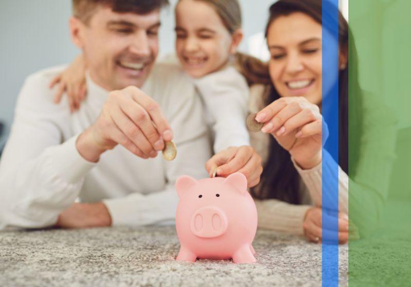 Two parents and their young daughter putting coins in a piggy bank