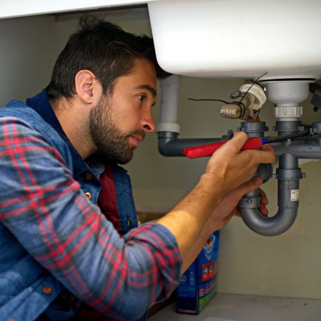 plumbing contractor working on sink pipes