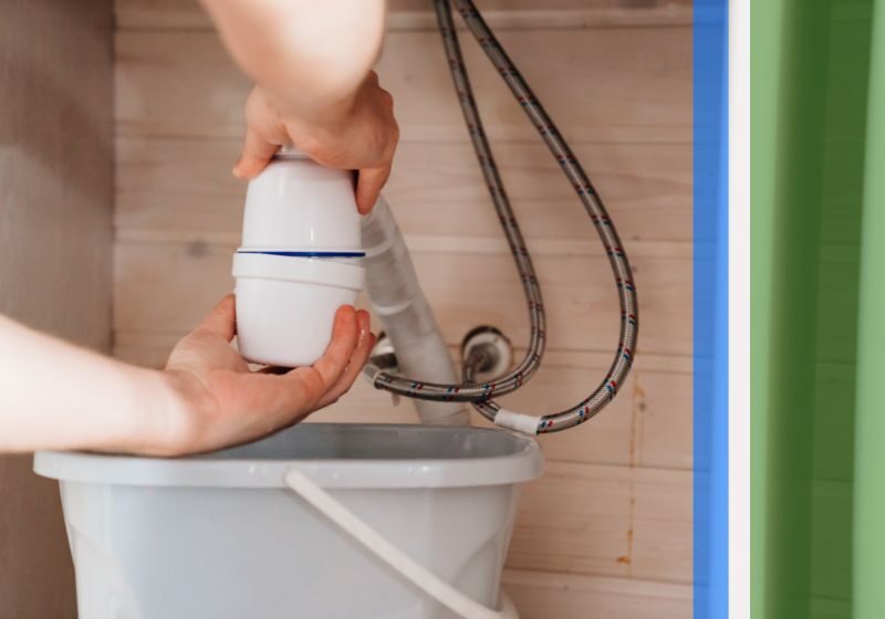 A plumber working on a disposal under a sink