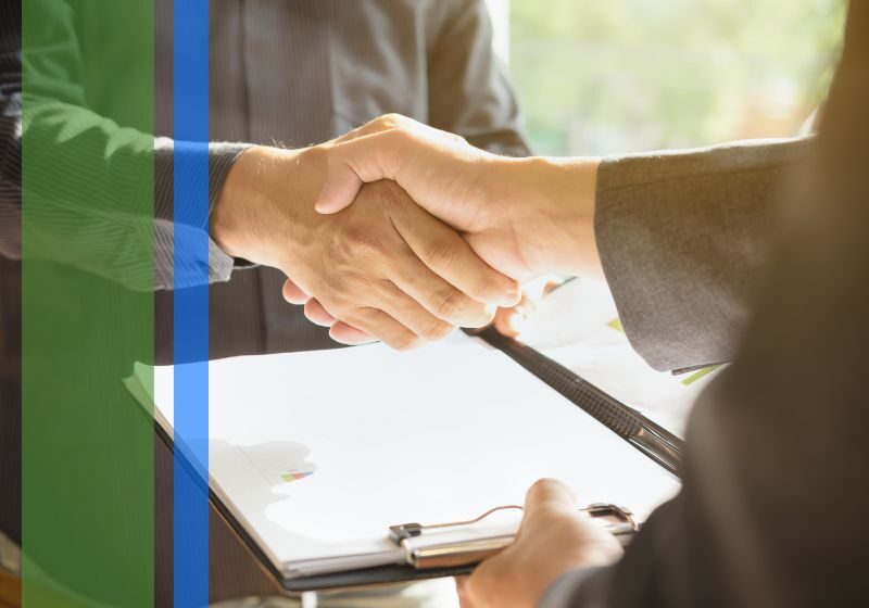 A plumber holding a clipboard shaking hands with a homeowner